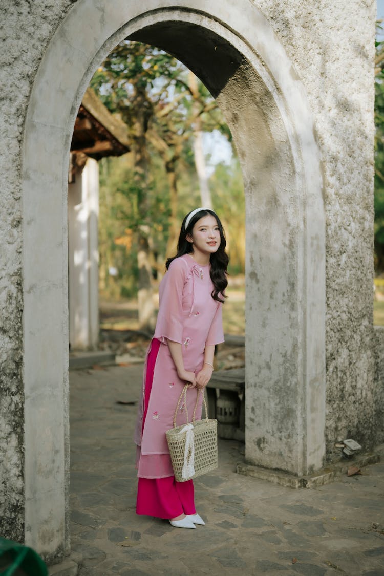 Young Woman In A Pink Ao Dai Dress Under An Arch 