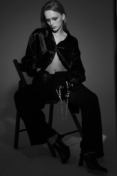 Striking black and white portrait of a woman in modern fashion, seated gracefully.