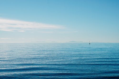 Free Peaceful ocean view with a lone boat on the horizon in Marbella, Spain. Stock Photo