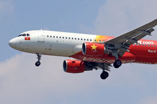 Free VietJet Air Airbus A320 flying in clear sky with landing gear extended. Stock Photo