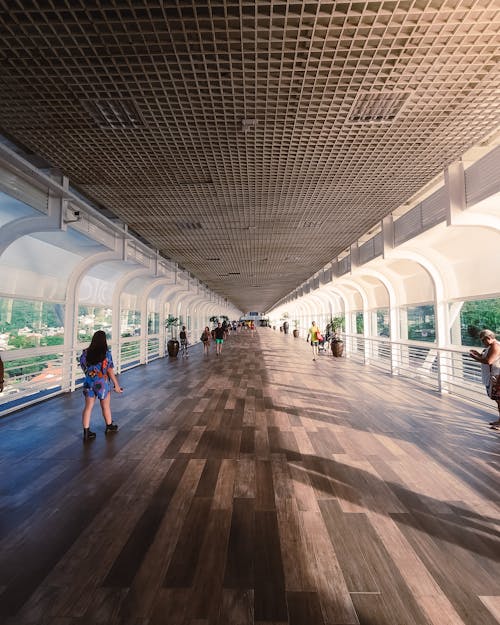 People walking on a long walkway with a wooden floor