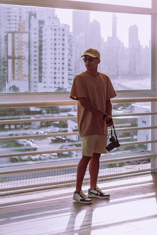 City Buildings behind Man in Cap and T-shirt