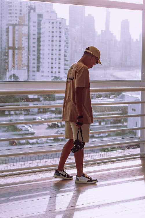 A man in a hat and shorts standing on a balcony