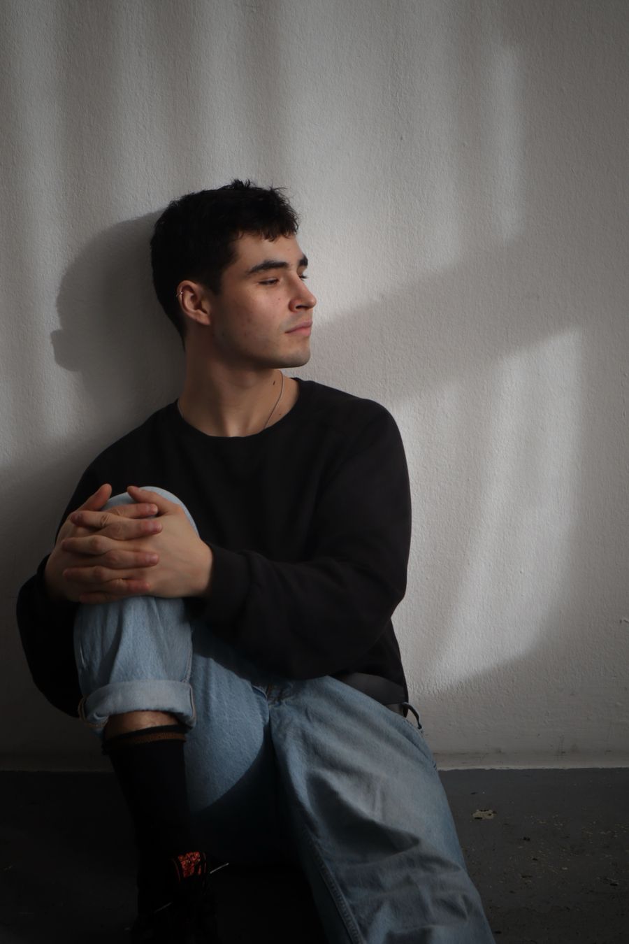 Model wearing a plain black long-sleeve top against a lit wall — photo by Meike on Pexels