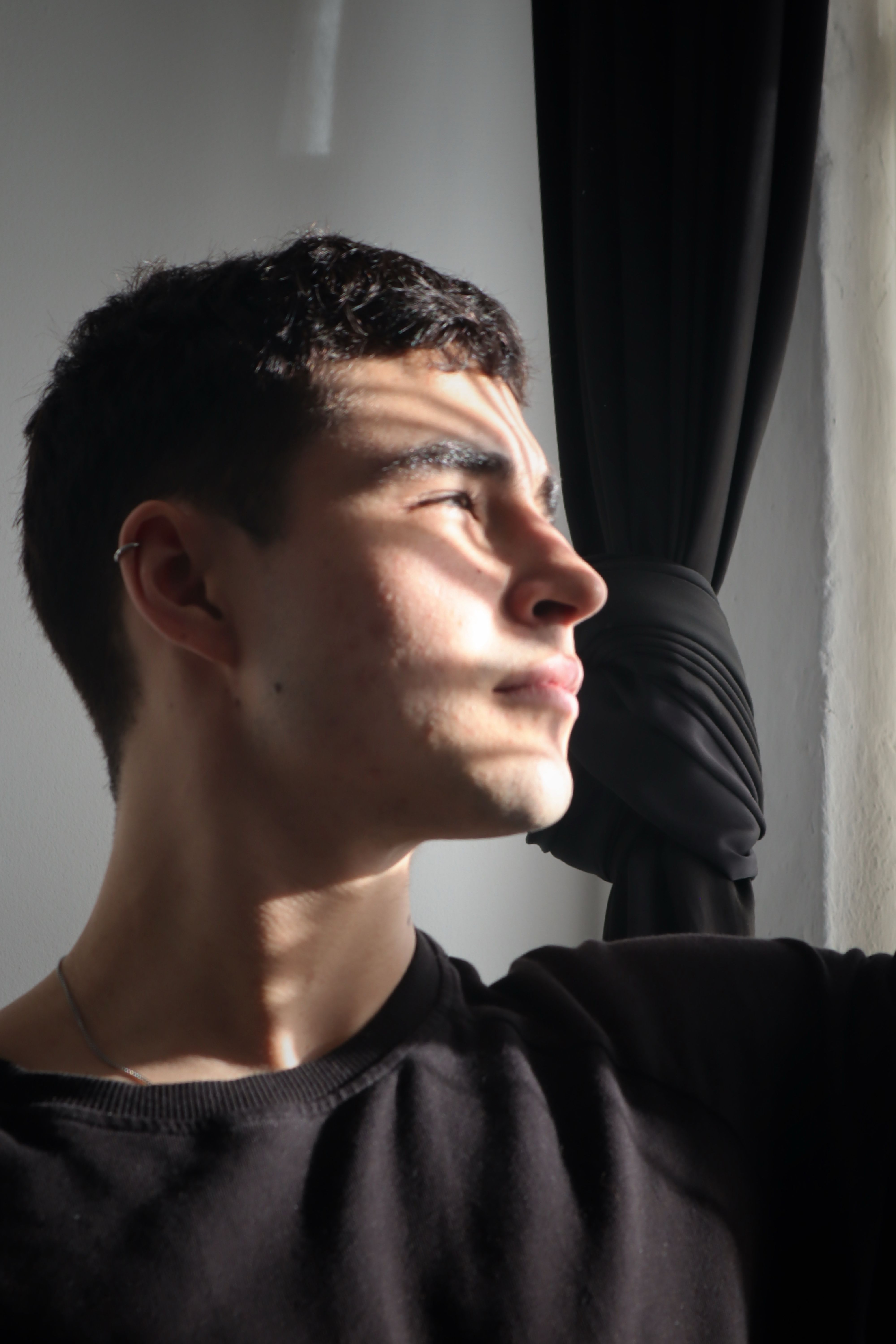 Portrait of a young man looking thoughtfully out the window in Berlin.