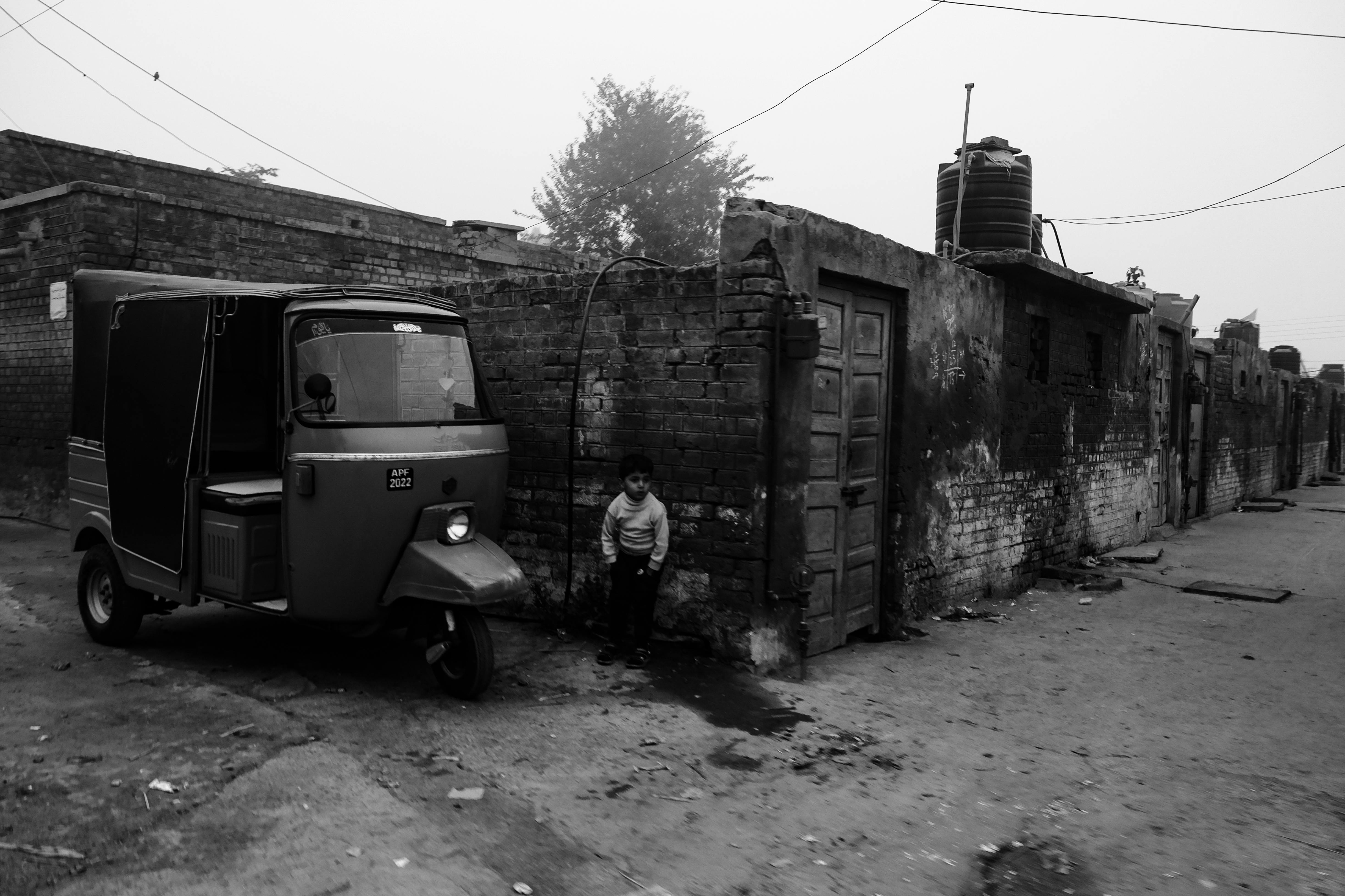 boy standing near three wheeler in village