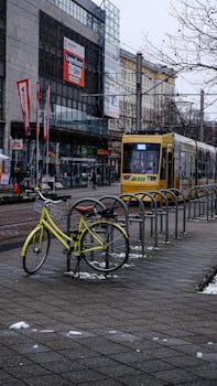 Winter urban scene in Magdeburg featuring a yellow tram and bicycle on a snowy sidewalk.