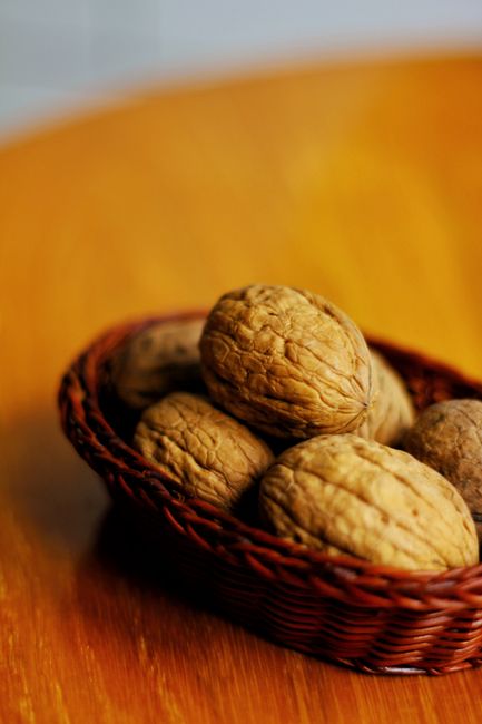 Hạt óc chó - siêu thực phẩm cho não bộ 4 A detailed shot of walnuts in a basket on a wooden table, providing a rustic feel.