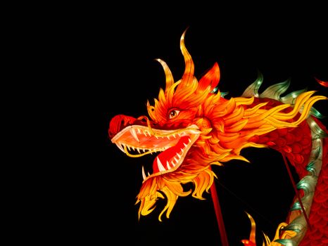 Colorful illuminated dragon lantern glowing against black night sky.