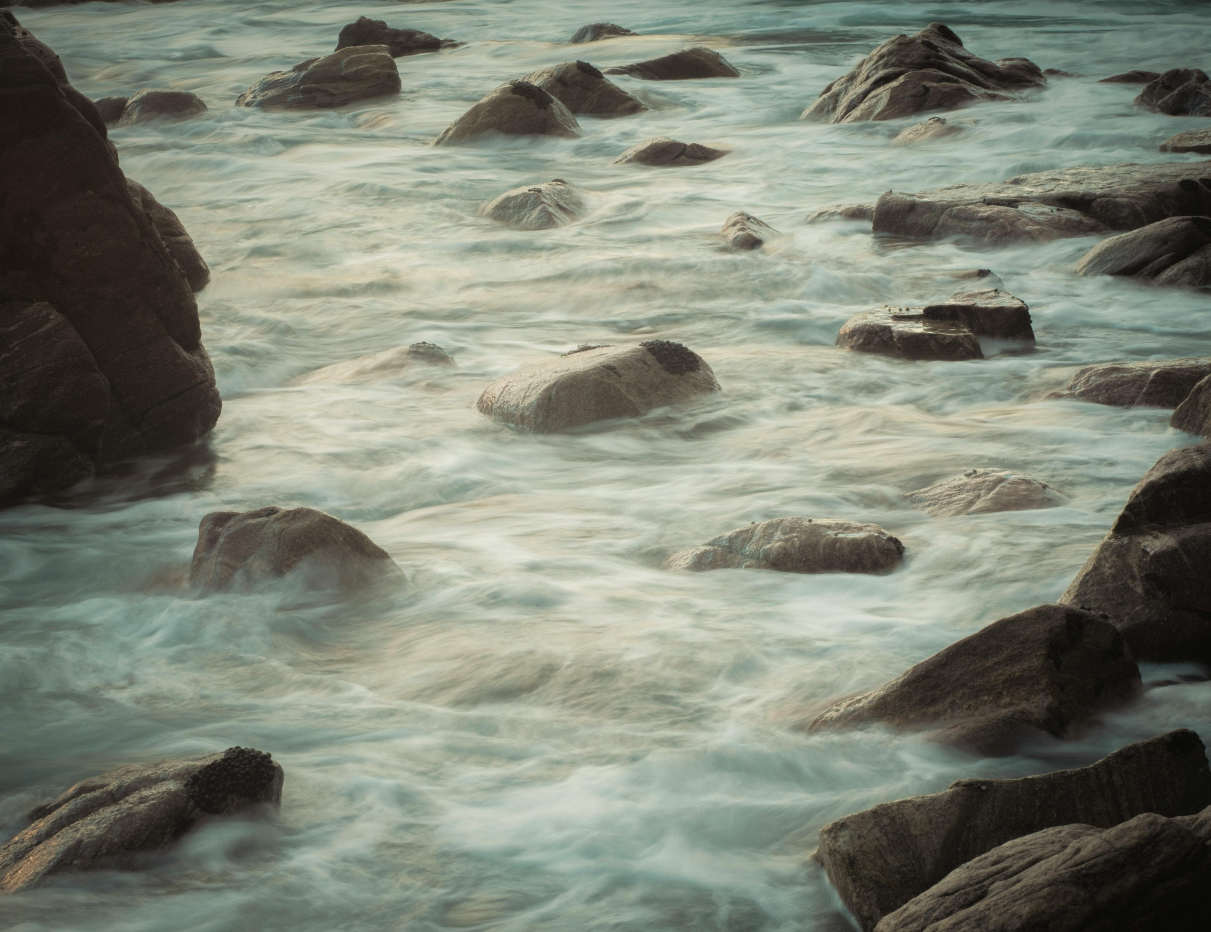 Tranquil image of a rocky coastline with smooth, flowing waves creating a peaceful atmosphere.