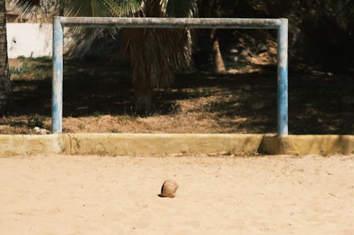 A soccer ball on the sand near a goal