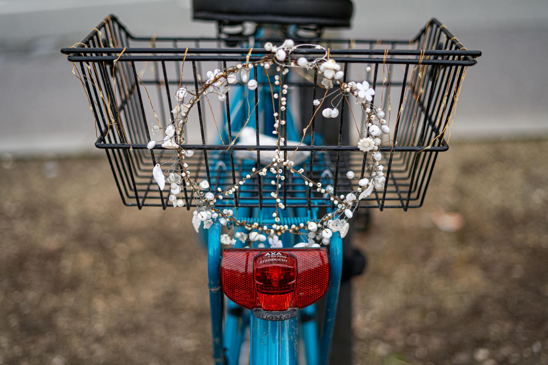 Blue bike with pearl peace sign on basket in urban setting.