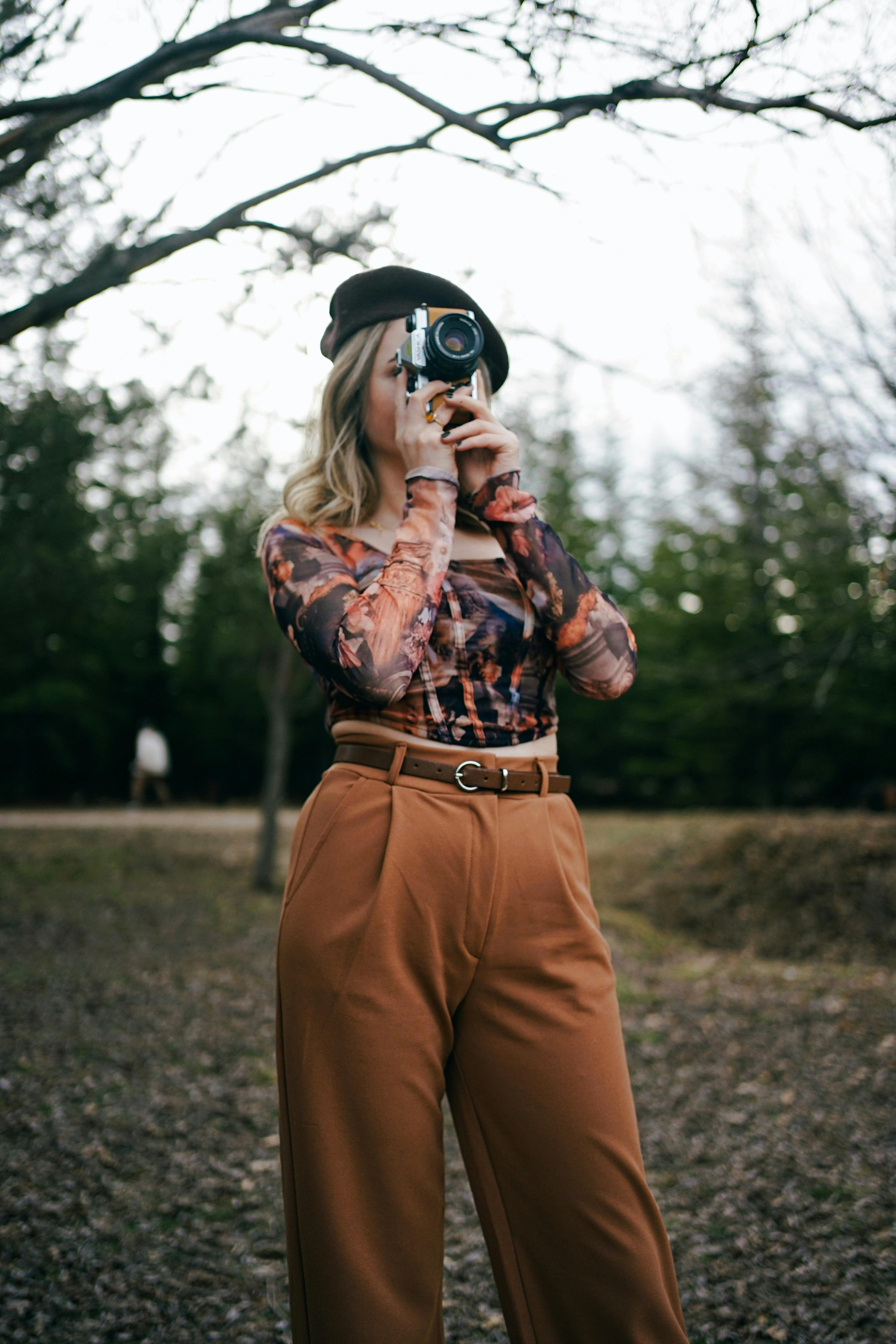 Stylish woman using analog camera in Ankara park during fall season.