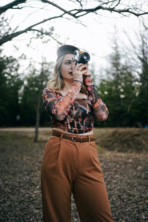 Free Blonde Woman in Brown Pants Taking Photo in Park Stock Photo