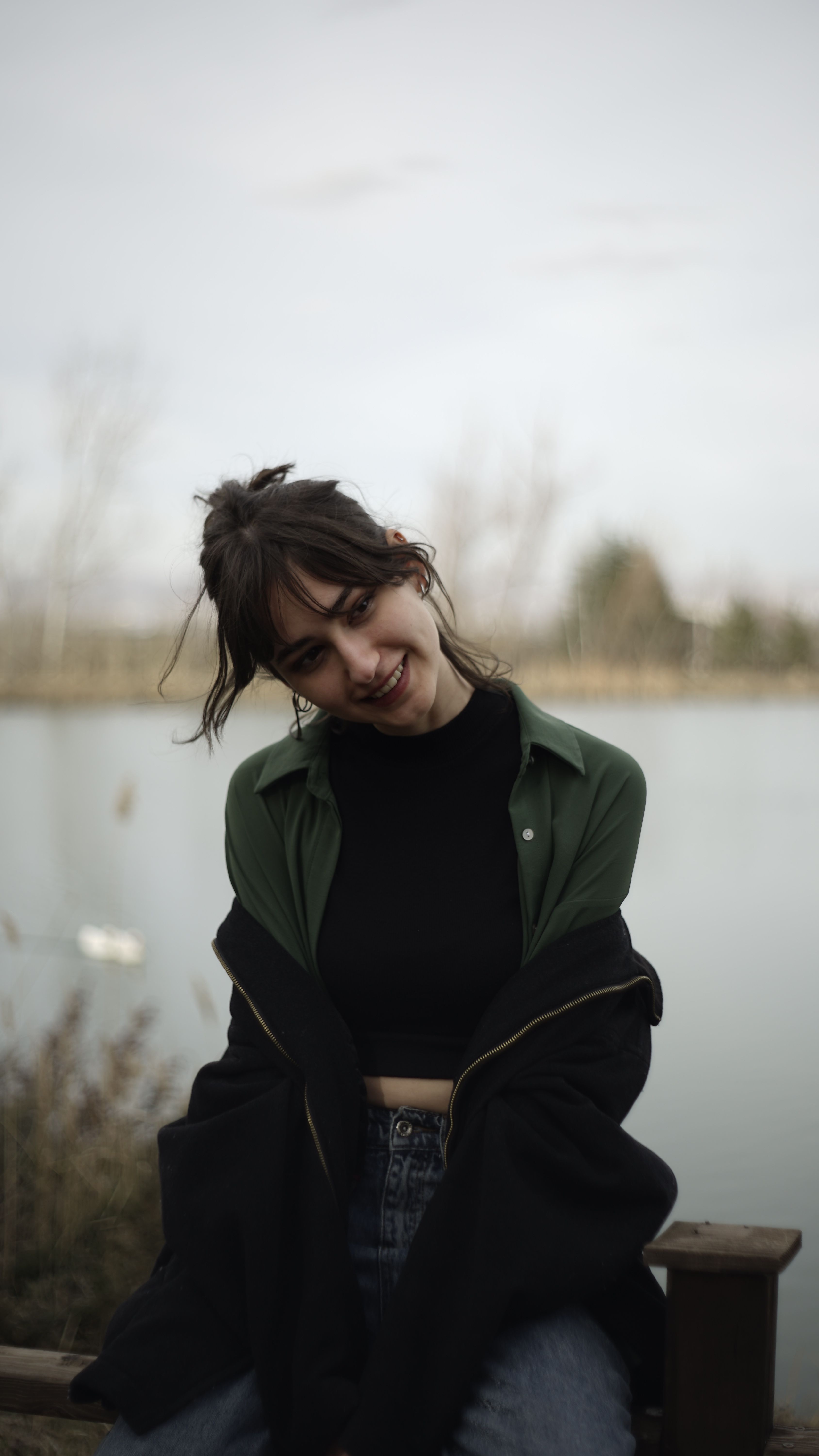 A young woman smiling in front of a serene lake backdrop in Ankara, Türkiye.