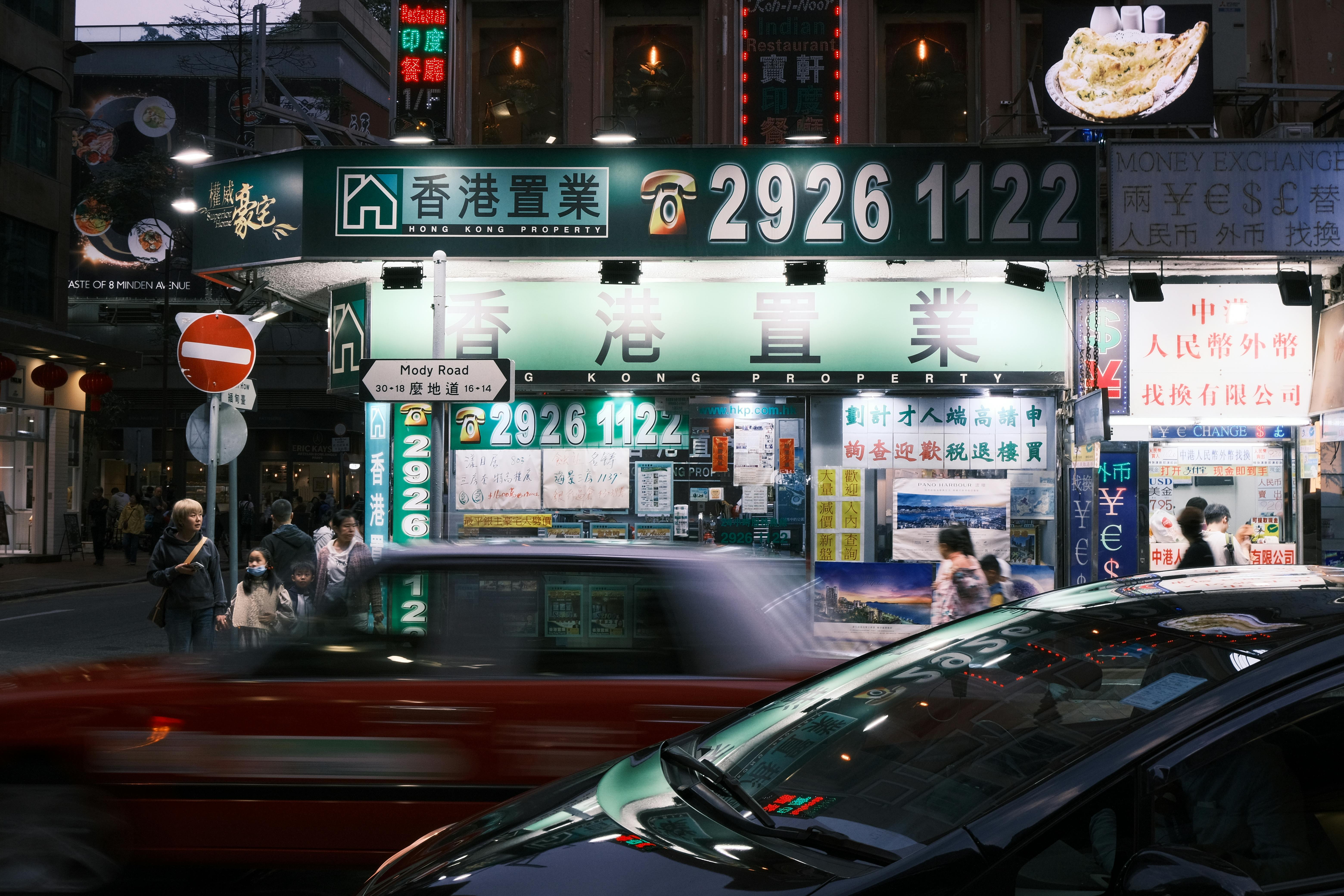 A bustling night scene on Mody Road, Hong Kong featuring bright lights and urban activity.