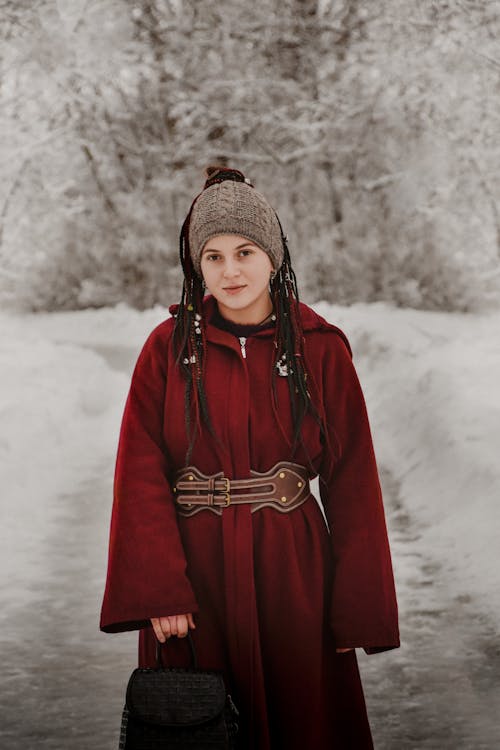 A young girl in a red coat and hat standing in the snow