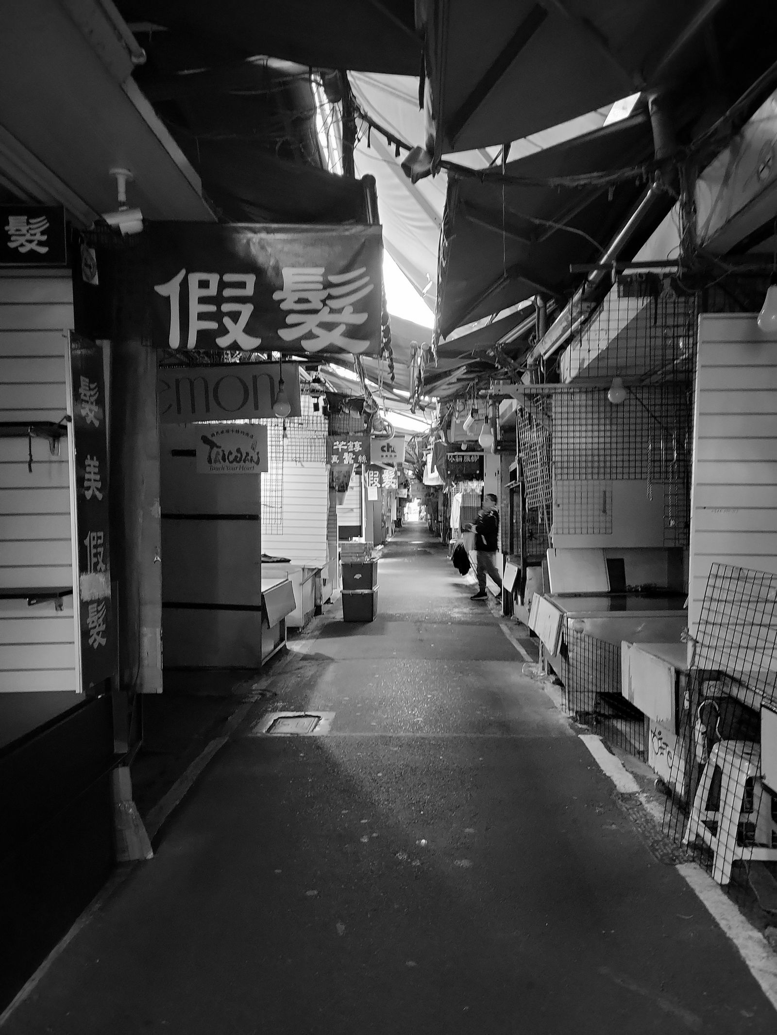 Black and white photograph of an empty market alleyway