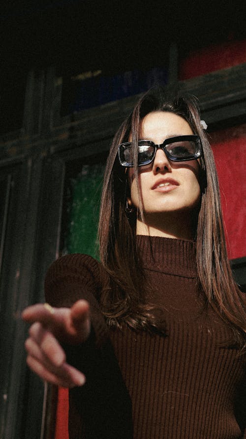 A Young Woman in Sunglasses Posing with Pointing her Fingers