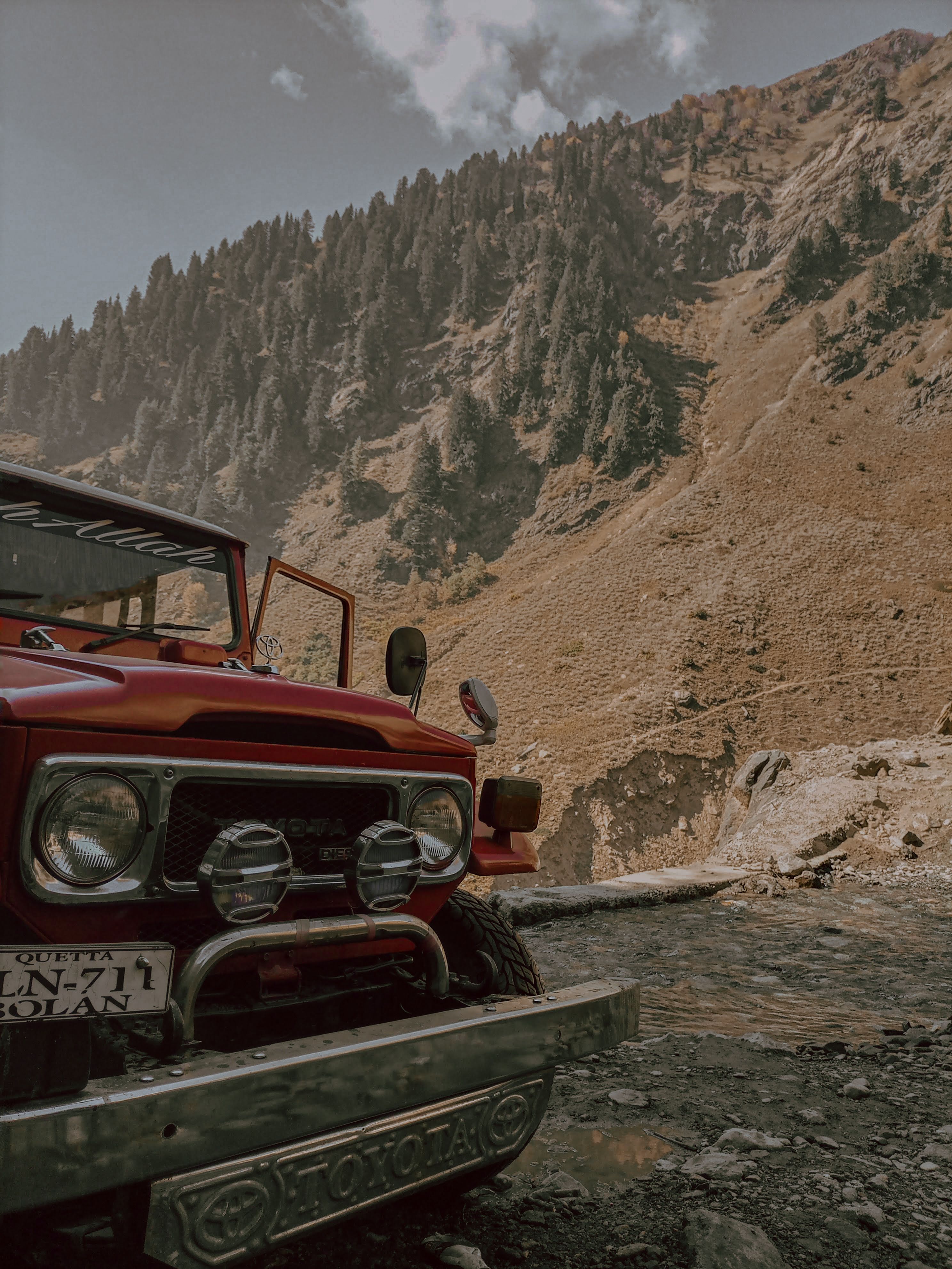 A vintage red 4x4 vehicle parked in a stunning mountain setting, perfect for adventure visuals.