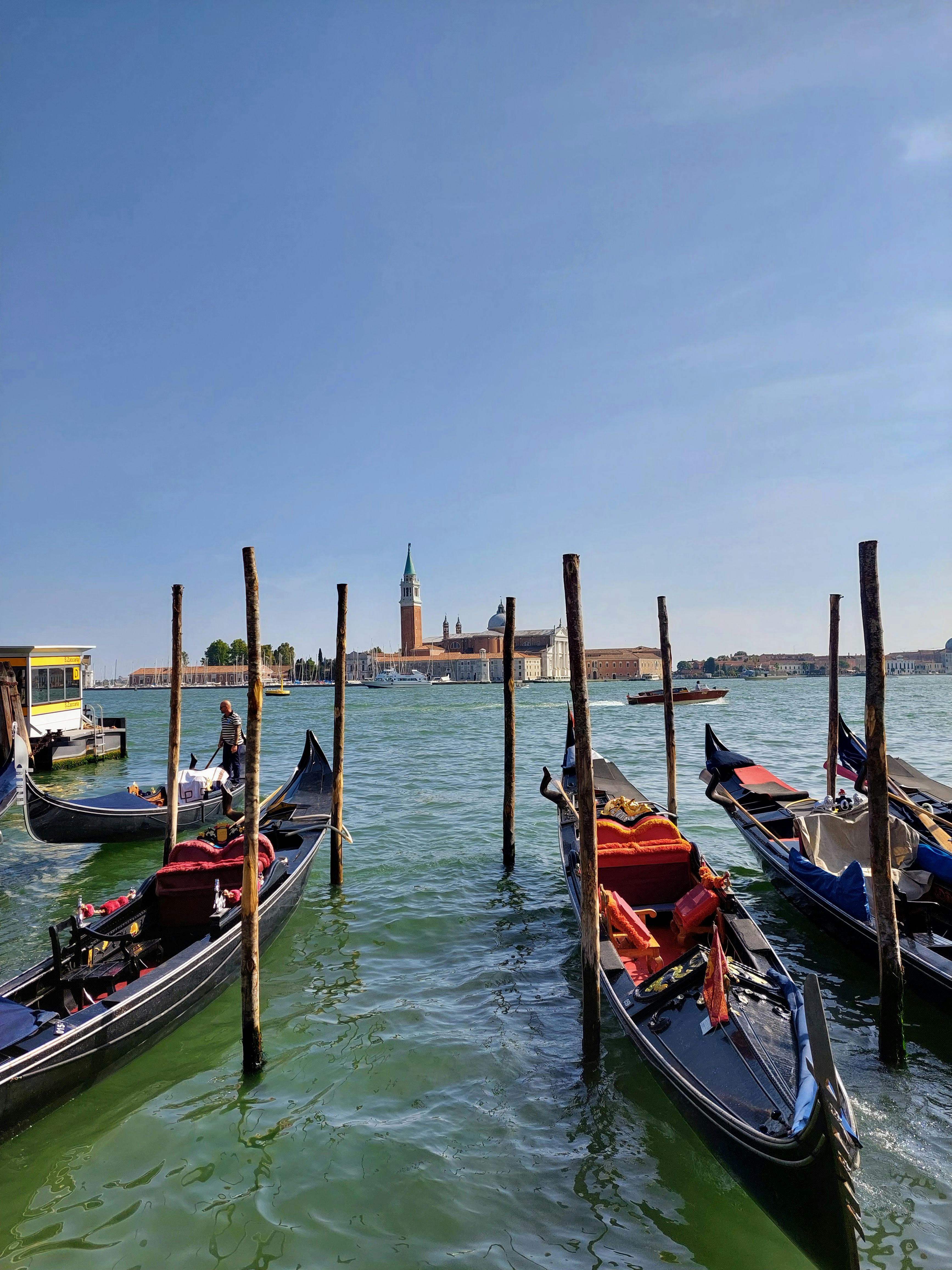 Beautiful view of gondolas docked by the Venice lagoon with historic architecture in the background.