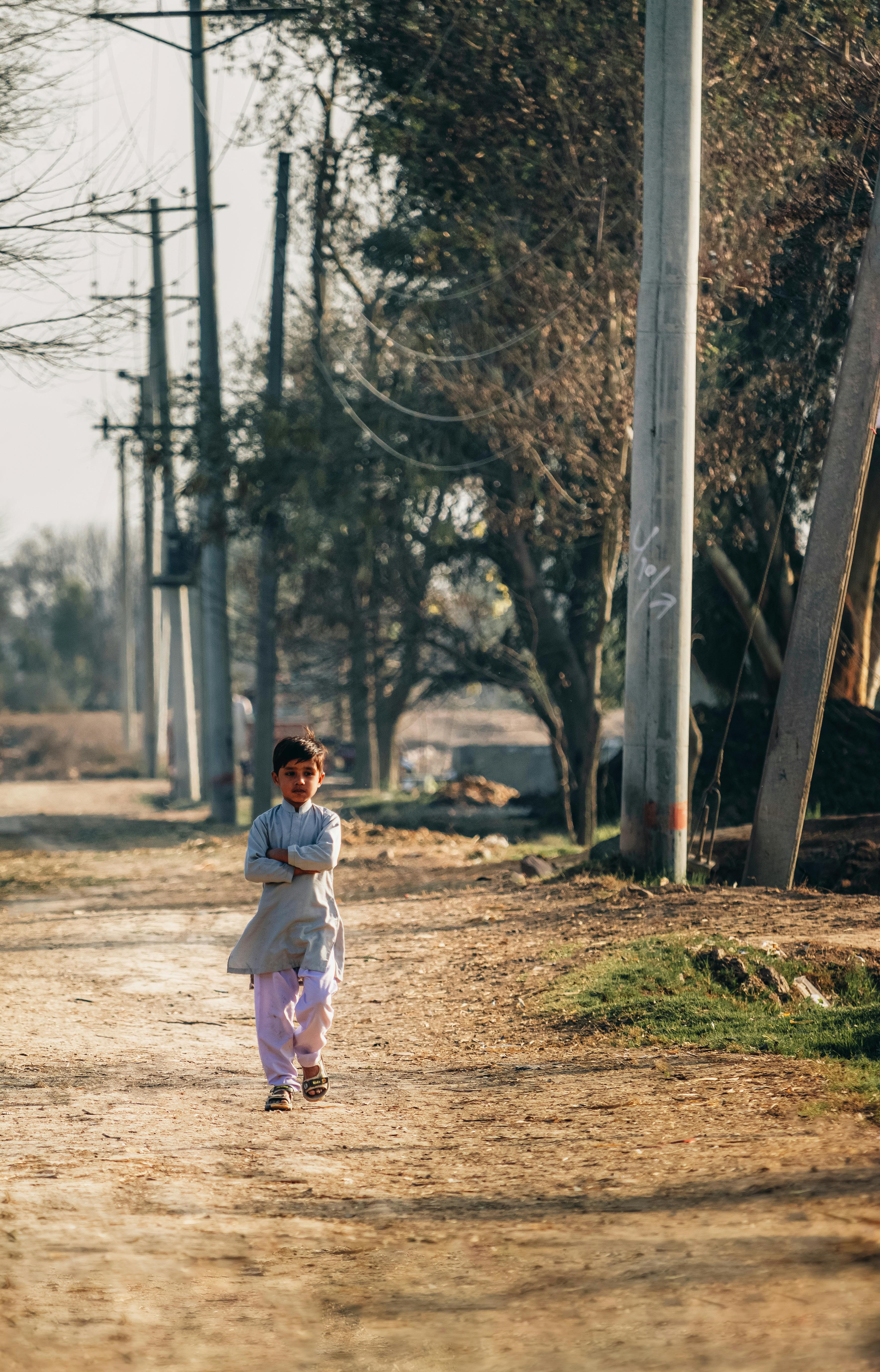 little boy walking by the electricity poles