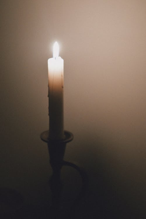A candle is lit in the dark with a foggy background