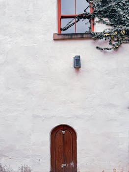An ivy-covered urban wall featuring a wooden arched door and window in Leeds, UK.