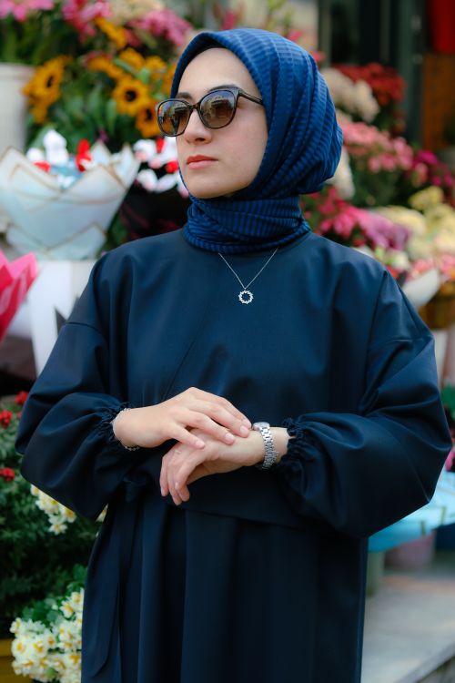 Free Portrait of a stylish Muslim woman wearing a hijab and sunglasses, standing in front of a vibrant flower market. Stock Photo