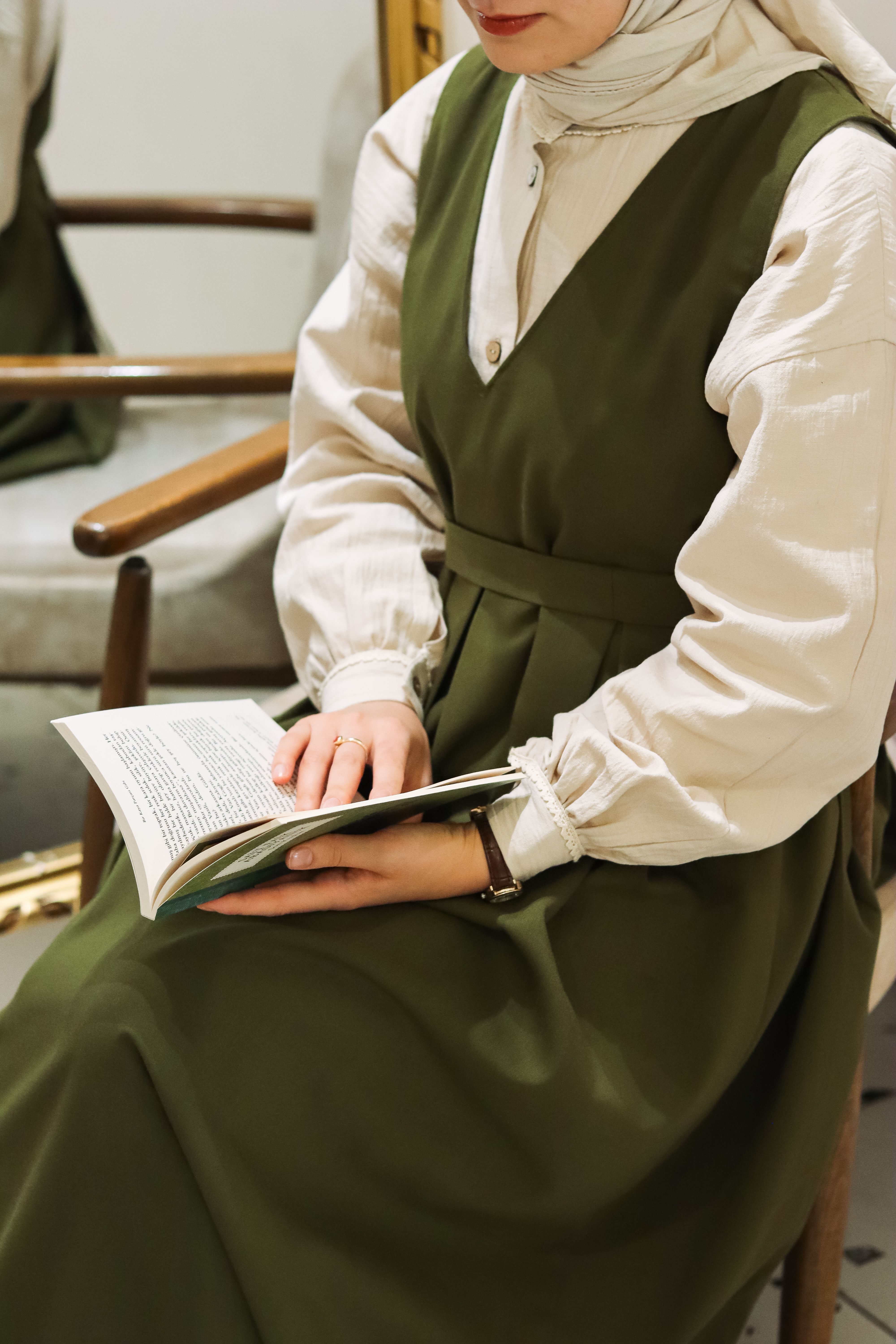 Woman in Hijab and Green Dress Sitting with Book  Free Stock Photo