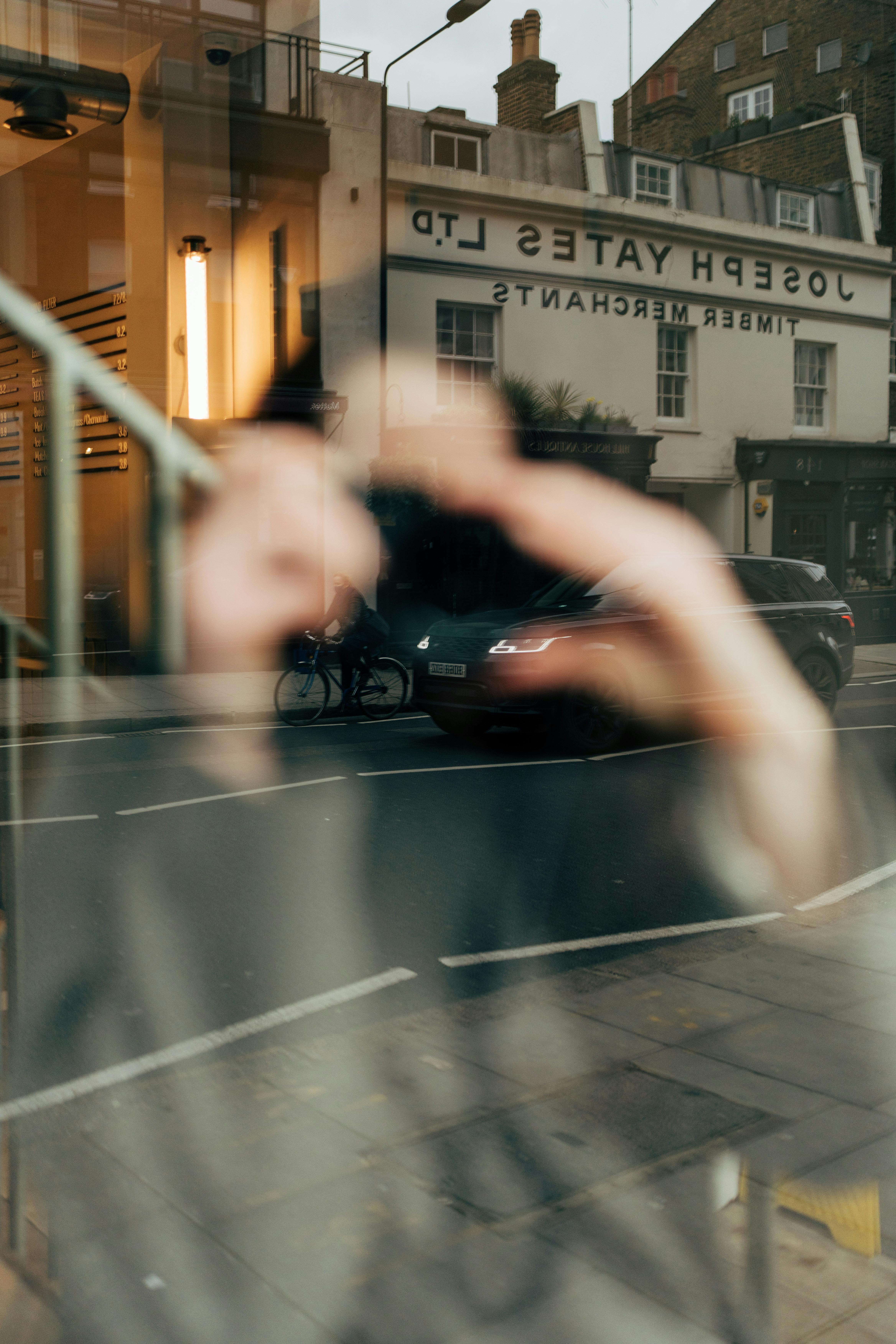Artistic reflection of city street in London with blurred figure, capturing urban atmosphere.