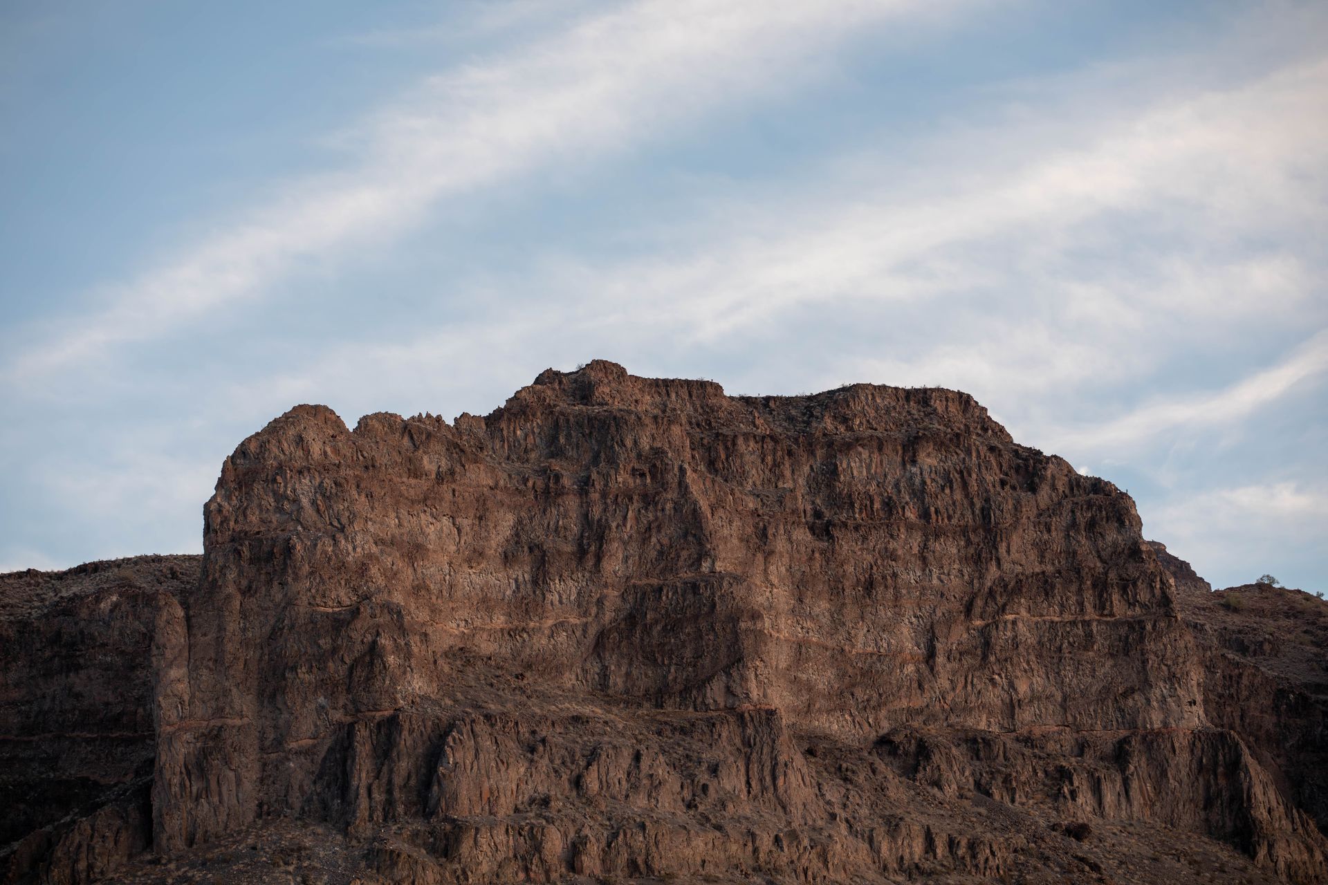 Majestic rocky mesa under blue sky in Parker, AZ, capturing nature's raw beauty.