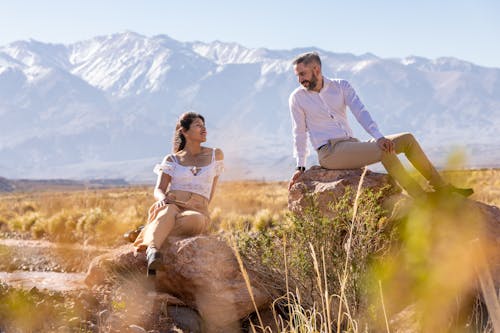 A couple sitting on rocks in front of mountains
