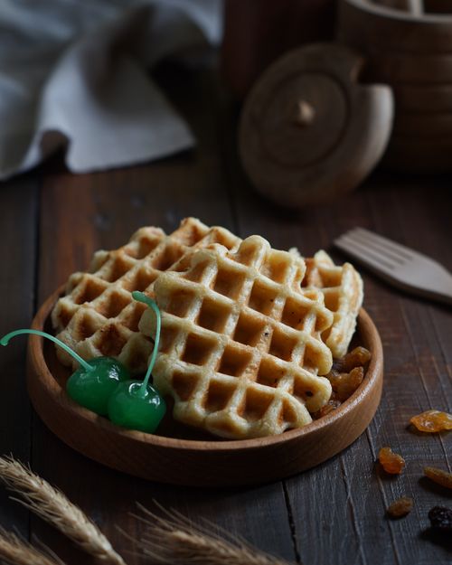 Free Tasty waffles on a wooden plate with green cherries, perfect for breakfast visuals. Stock Photo