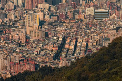 Free Stunning aerial panorama of a bustling city adjacent to a lush, green hillside. Stock Photo