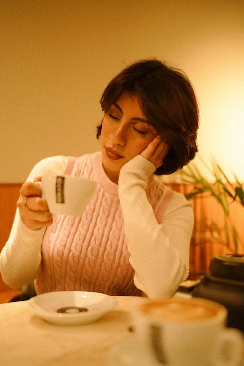 A woman sitting at a table with a cup of coffee