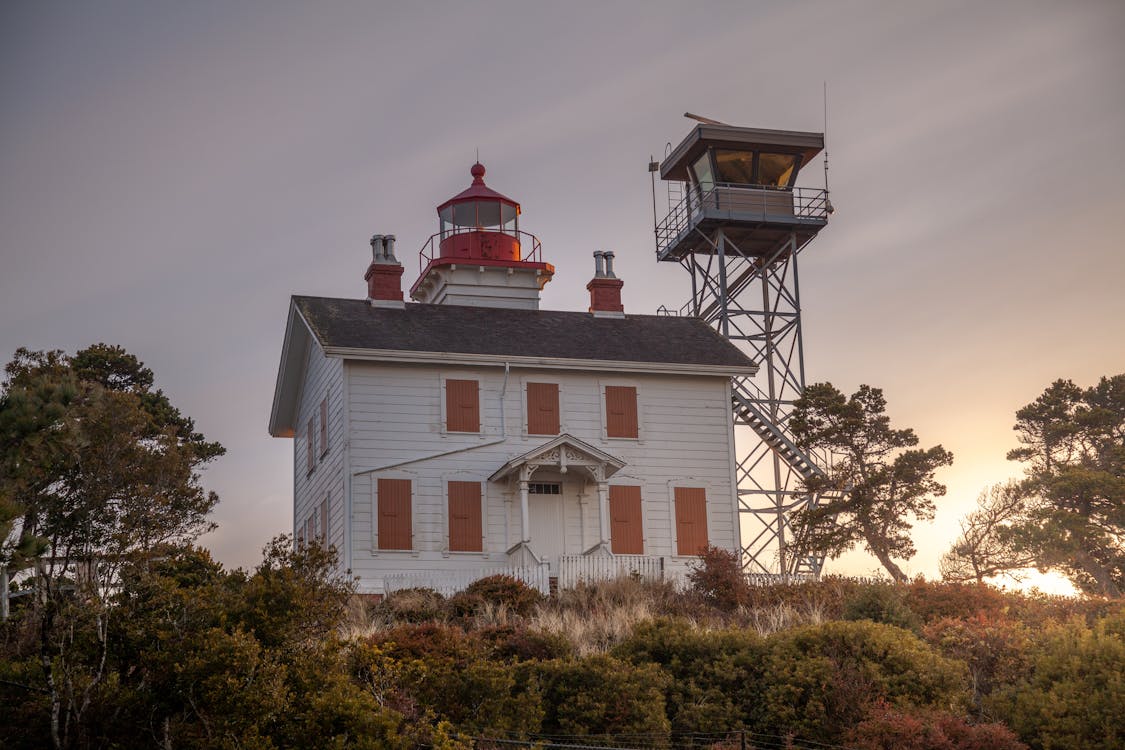 Tower Beside Lighthouse Under Cloudy Sky