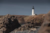 俄勒冈州海岸矗立的灯塔的戏剧性景色，周围环绕着崎岖的悬崖