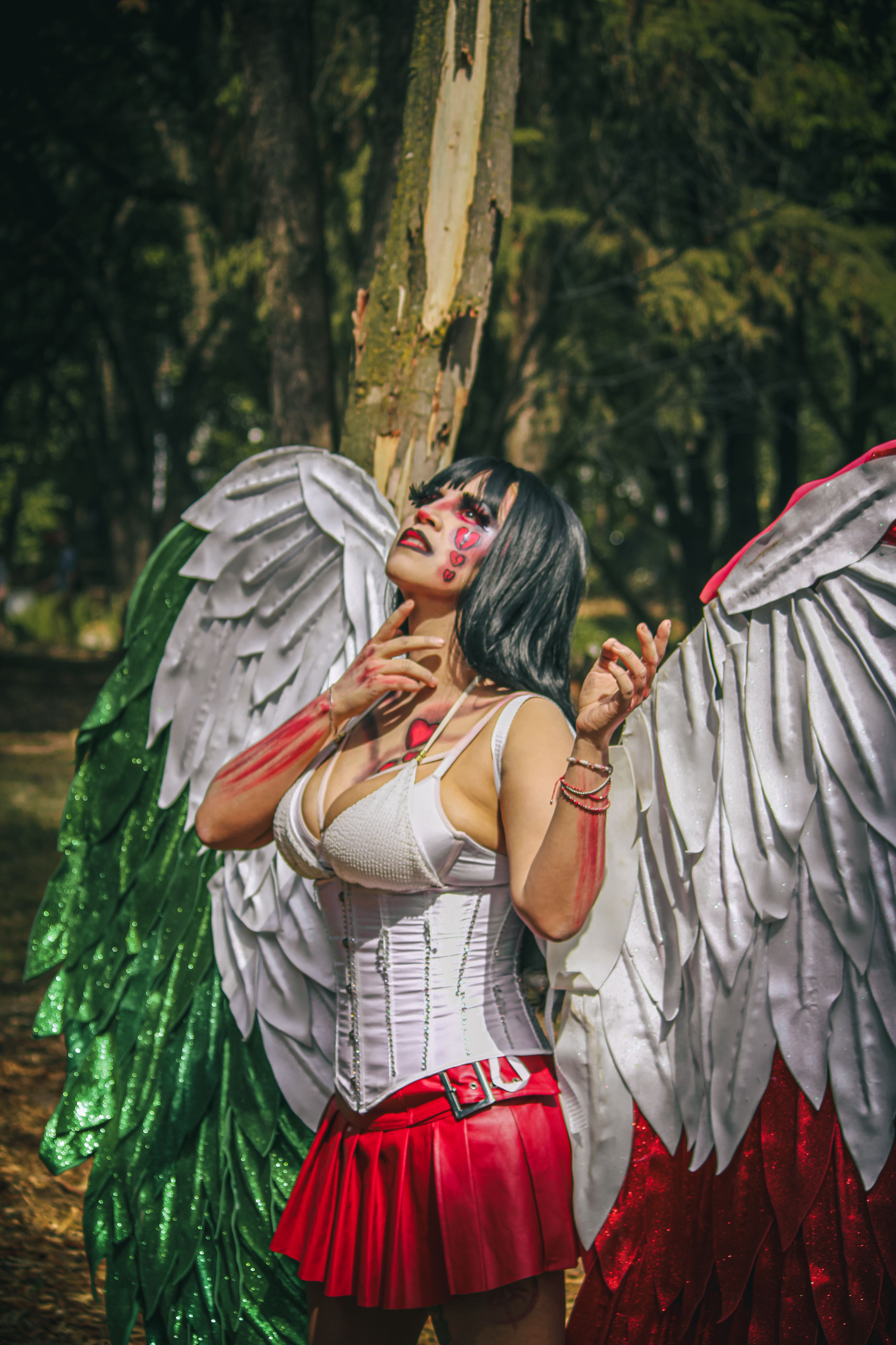 A performer in a vibrant costume with angel wings posing outdoors in Mexico City.