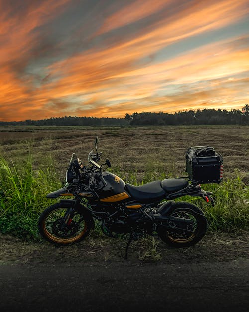 A motorcycle parked in the middle of a field at sunset