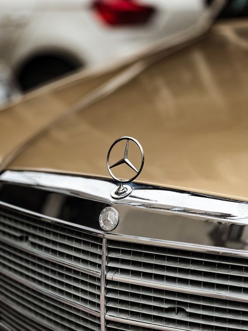 Free Detailed view of a vintage car logo and front grill, symbolizing luxury and elegance. Stock Photo