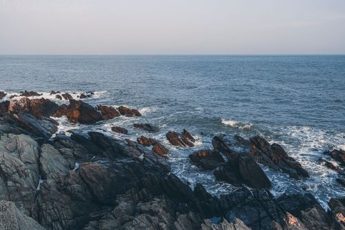 Free Serene view of rocky seaside with waves crashing on a calm day. Stock Photo