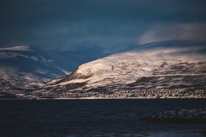 A snowbound coastal town beneath dark winter peaks — photo by Francesco Ungaro on Pexels