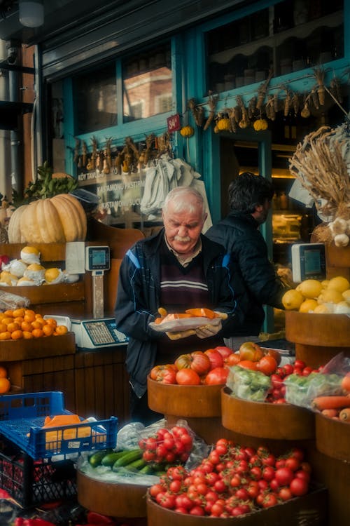 Free An older man is standing in front of a fruit stand Stock Photo