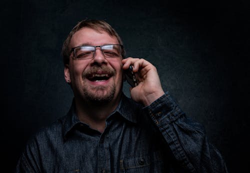Человек смеется при использовании мобильного телефона