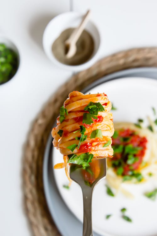 Close-up of Pasta with Tomato Sauce and Herbs on a Fork 