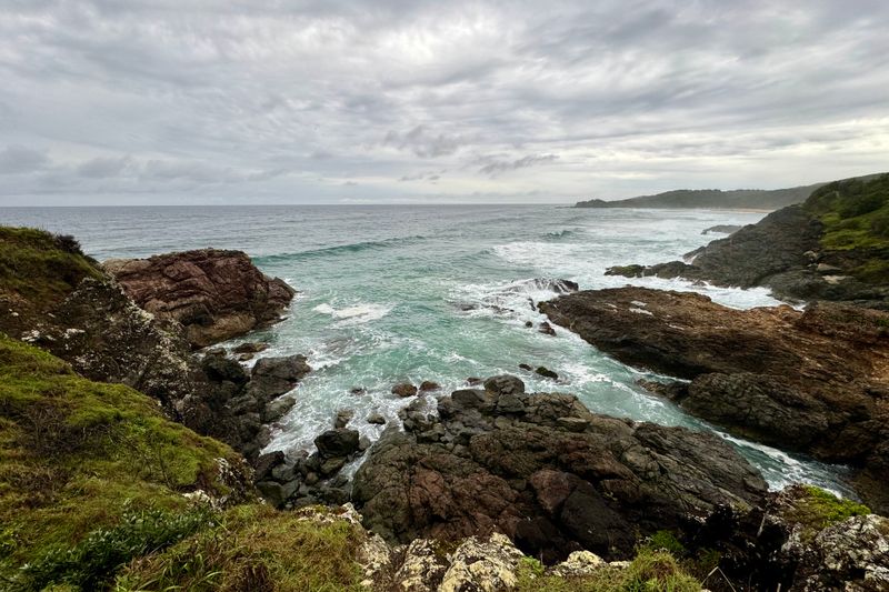 Explore a rugged coastline with dramatic cliffs and crashing ocean waves.