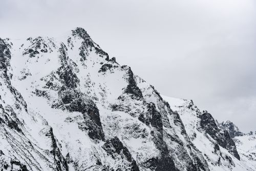 Free A breathtaking view of a snowcapped mountain range under a cloudy sky, capturing the rugged beauty of winter. Stock Photo