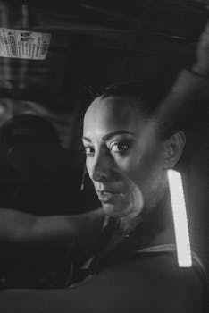 A striking black and white portrait of a woman in a dimly lit car, exuding a cinematic and moody vibe.
