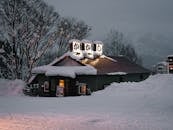 北海道新雪谷的冬夜，白雪皑皑，餐厅被积雪覆盖，呈现出一幅迷人的季节性场景